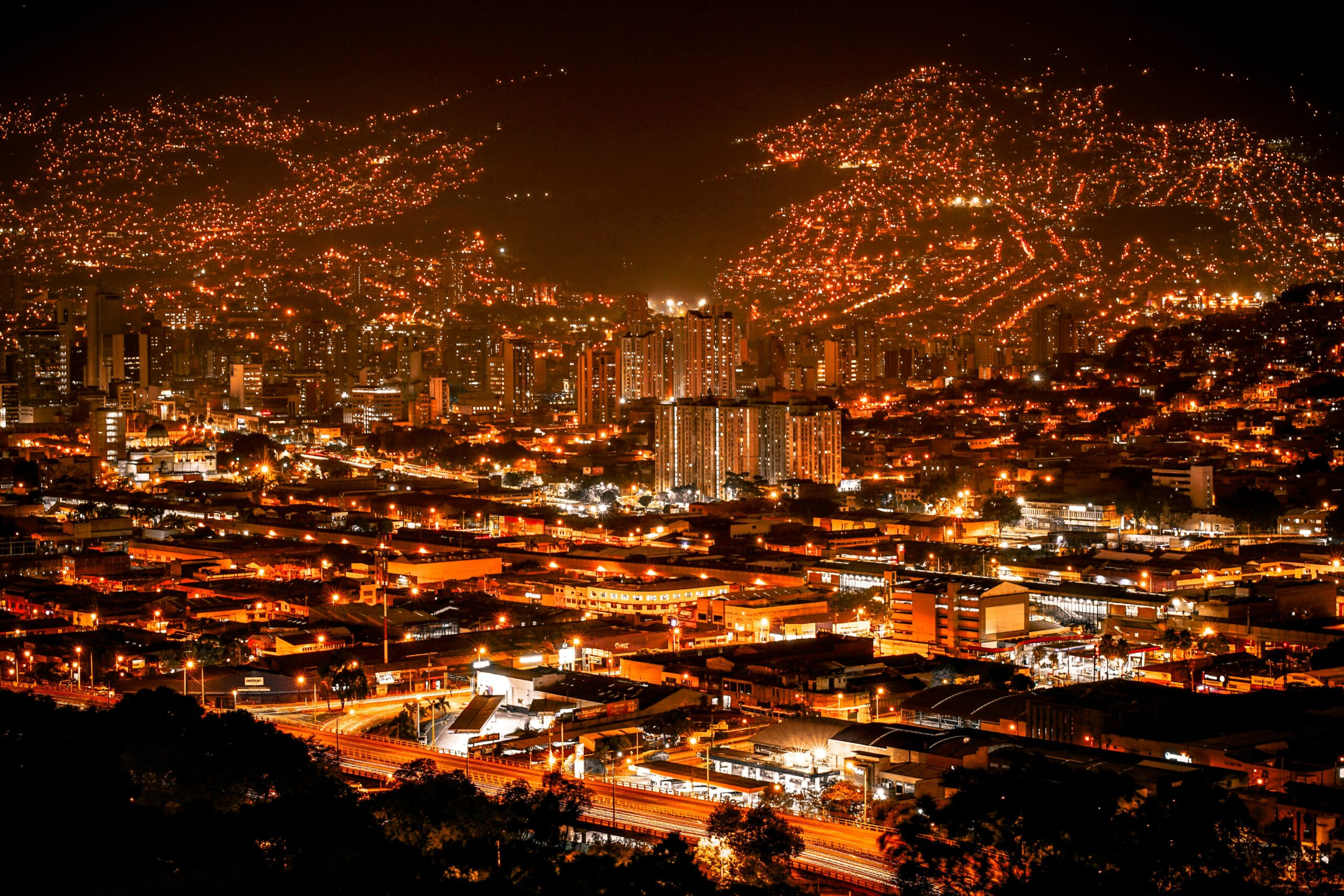 A vibrant aerial view of Medellín's illuminated skyline at night, showcasing the bustling urban landscape.