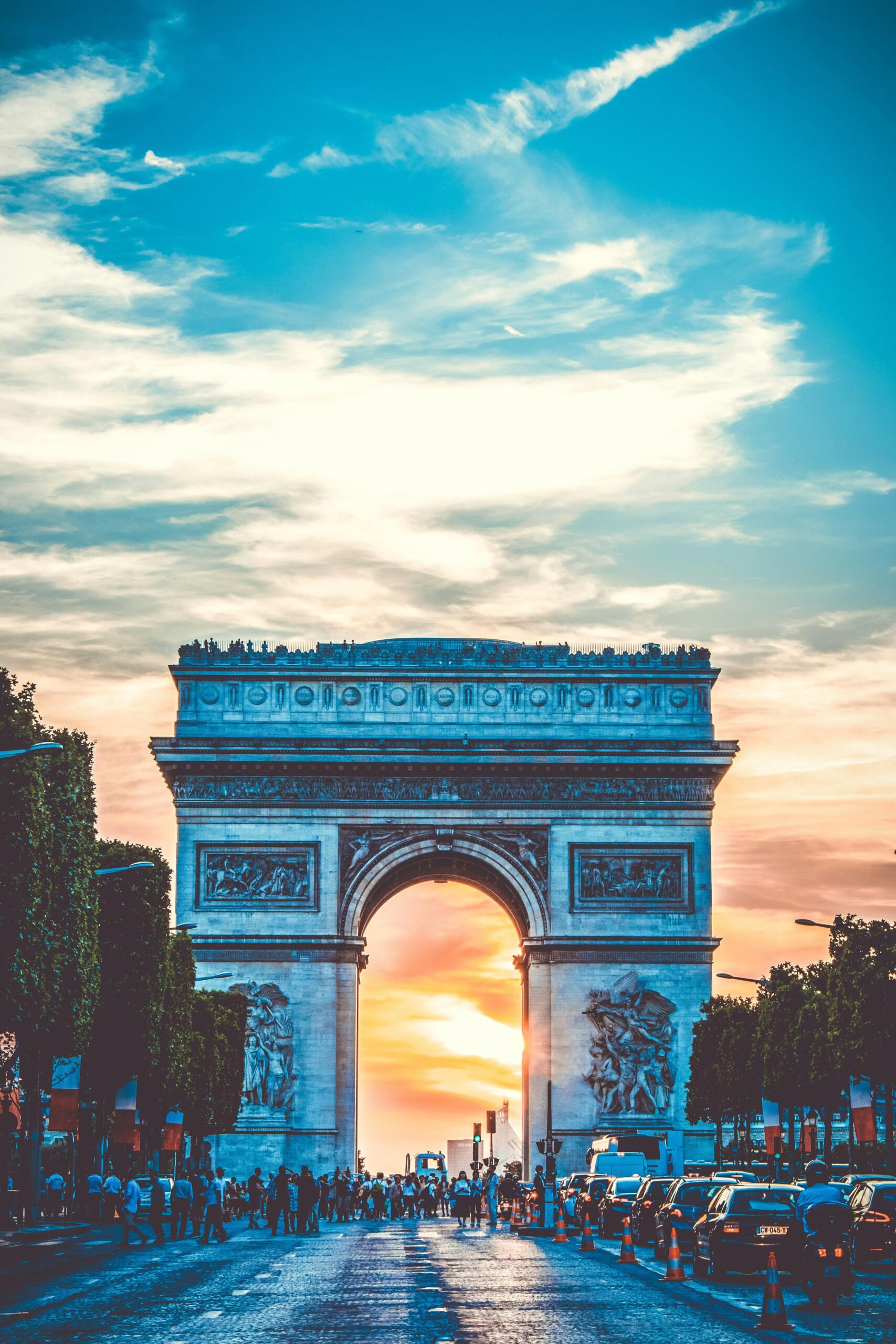Capture of the Arc de Triomphe at sunset with bustling Paris street life.